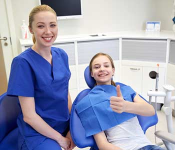 happy female dentist with patient girl at dental clinic office